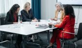 Businesswomen collaborating around a table in a modern office for a meeting.